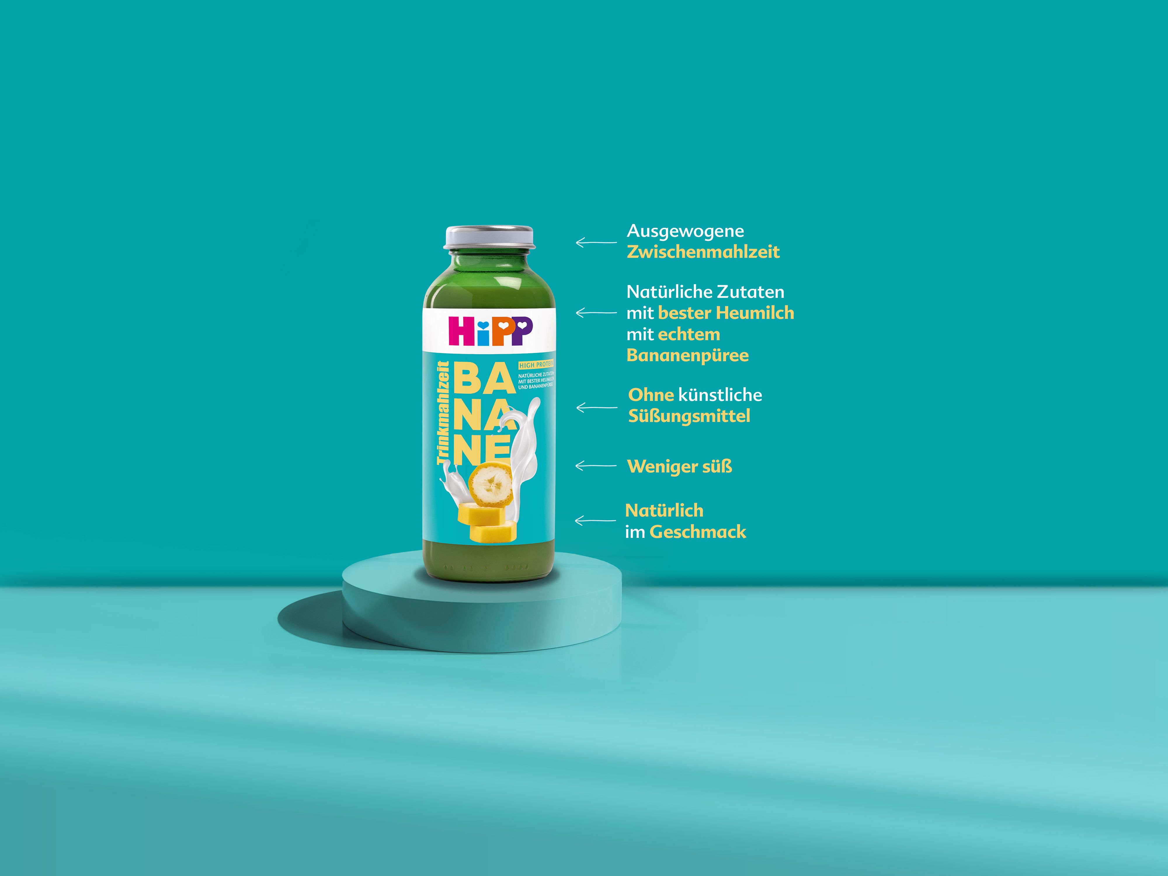 Flasche HiPP Trinkmahlzeit Banane mit Text zu natürlichen Zutaten, ohne künstliche Süßungsmittel und weniger süß auf türkisfarbenem Hintergrund