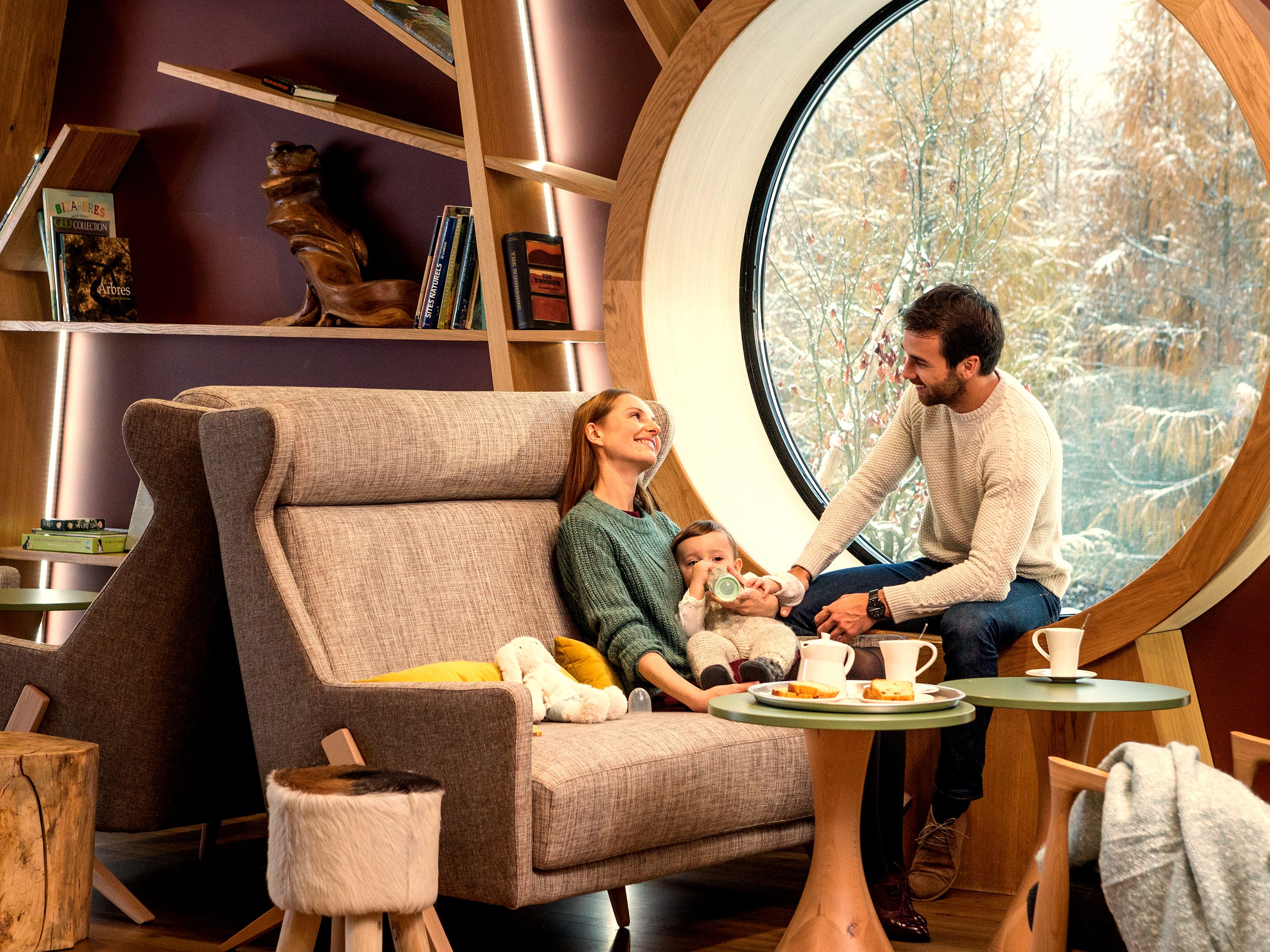 Familie sitzt im Ferienhaus auf dem Sofa am Fenster