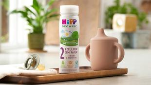 HiPP Organic follow on milk ready to feed on a wooden tray next to a beaker and dummy