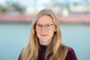 Kristin, lächelnde Ernährungswissenschaftlerin im HiPP Muttermilchforschungsteam, im Porträt vor unscharfem Hintergrund