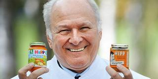 Claus Hipp holding 2 HiPP baby food jars