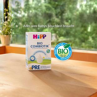 Packung HiPP Bio Combiotik PRE Babynahrung steht auf einem Holztisch vor einem Fenster mit Pflanzen im Hintergrund
