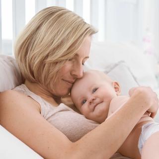 Ein zärtlicher Moment zwischen einer Mutter und ihrem Baby, wobei die Mutter das Baby sanft an ihr Gesicht drückt.