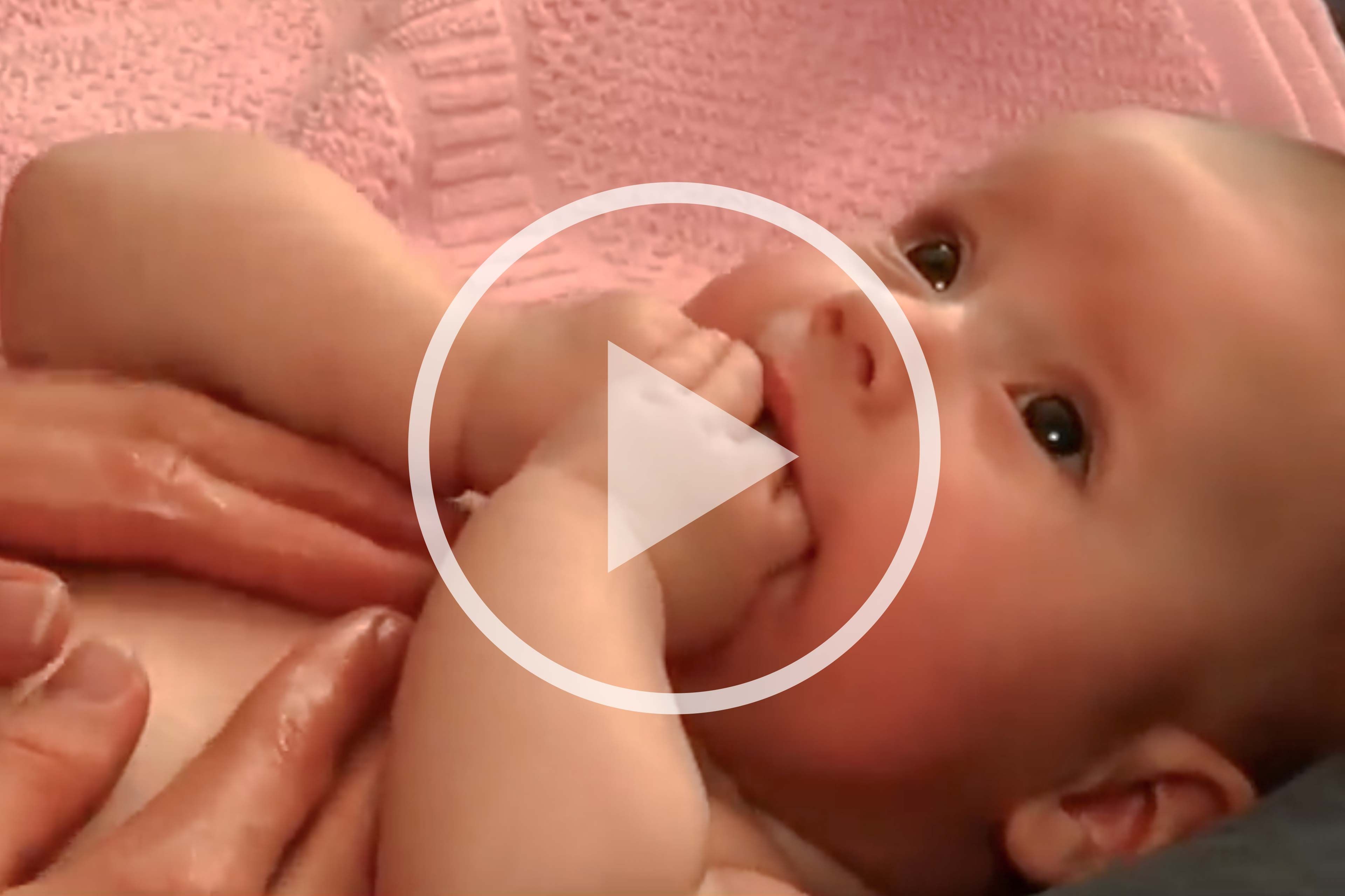 Nahaufnahme einer Hand, die sanft die Haut an der Schulter eines Babys berührt