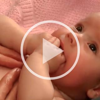 Nahaufnahme einer Hand, die sanft die Haut an der Schulter eines Babys berührt