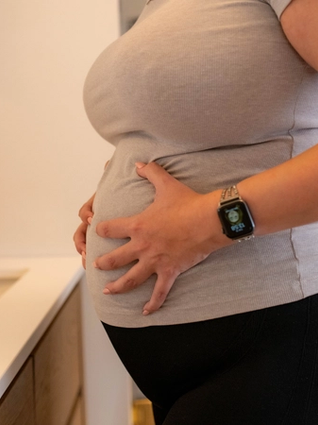 Close up of pregnant woman holding hips in pain