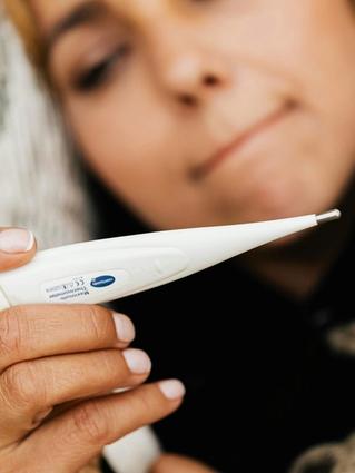 Woman closely checking a digital thermometer, illustrating basal body temperature tracking for family planning.