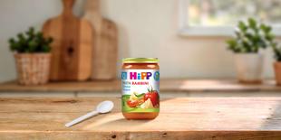 HiPP Pasta Bambini Gemüse-Lasagne Bio-Gläschen ab 10. Monat auf Holztisch mit Löffel in heller Küche
