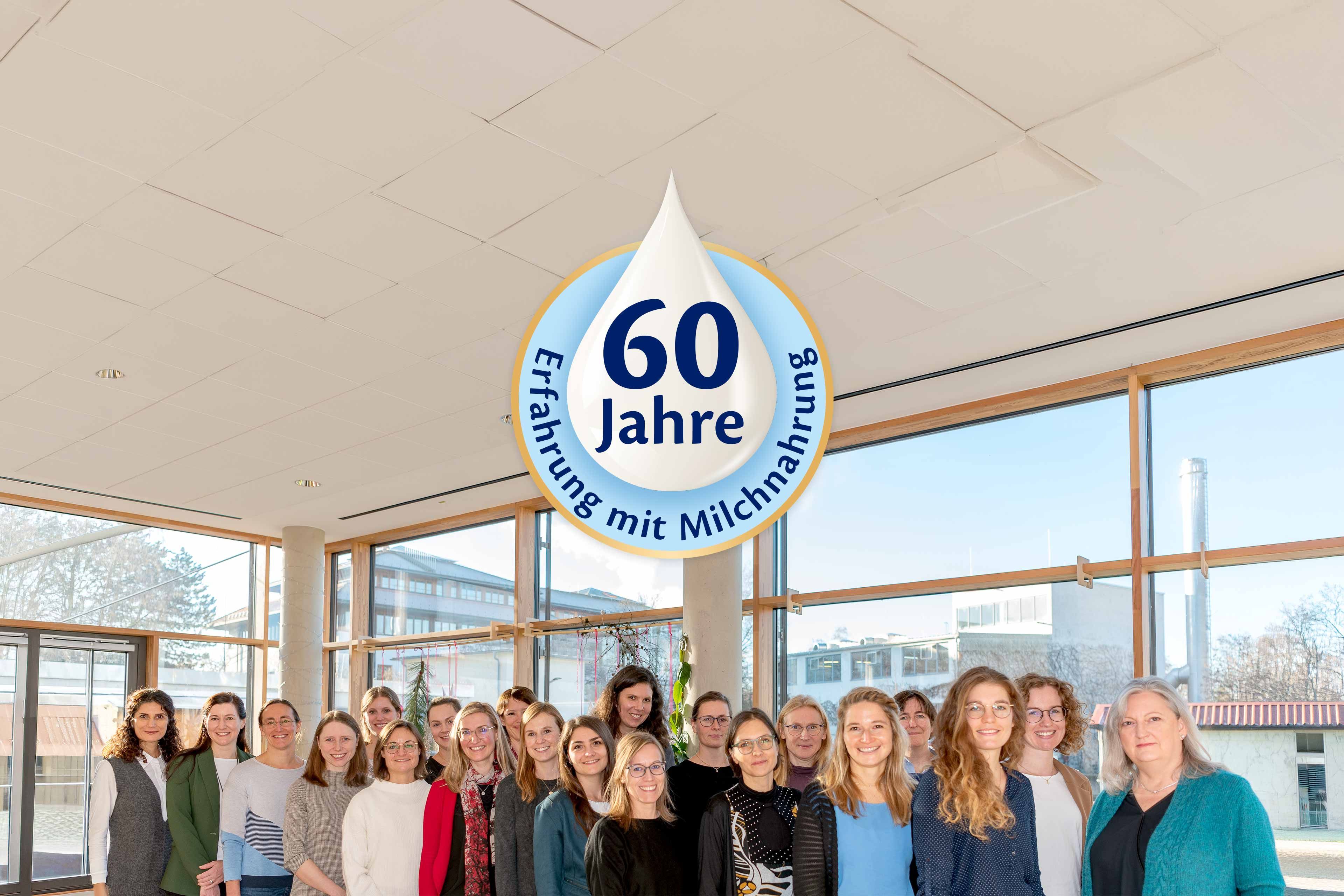 HiPP Forschungsteam zur Muttermilch vor Fenstern, darüber ein Logo mit „60 Jahre Erfahrung mit Milchnahrung“