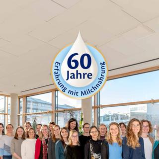 HiPP Forschungsteam zur Muttermilch vor Fenstern, darüber ein Logo mit „60 Jahre Erfahrung mit Milchnahrung“