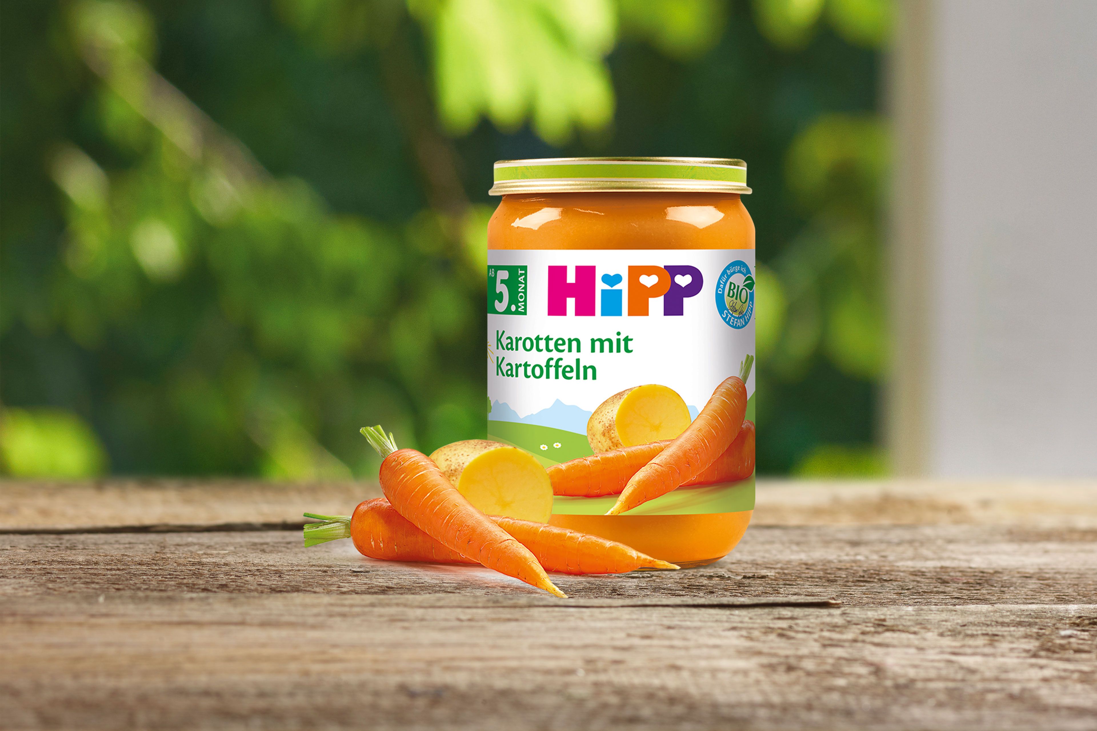 Das HiPP Gläschen Karotte mit Kartoffeln steht auf einem Holztisch
