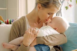 Mutter hält ihr Baby im Arm und berührt liebevoll Stirn an Stirn, ruhiger Moment vor dem Wiedereinstieg in den Beruf