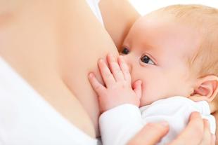 Ein Baby, das seine Hand auf die Brust der Mutter legt und zu säugen scheint.