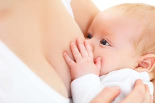 Ein Baby, das seine Hand auf die Brust der Mutter legt und zu säugen scheint.