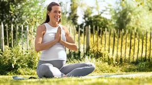 Eine Frau in einer ruhigen Umgebung im Freien, die mit ruhiger Miene Yoga praktiziert.