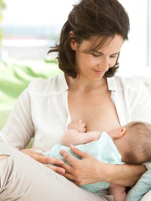 Eine Frau hält bequem ein Baby, das von ihr gestillt wird.