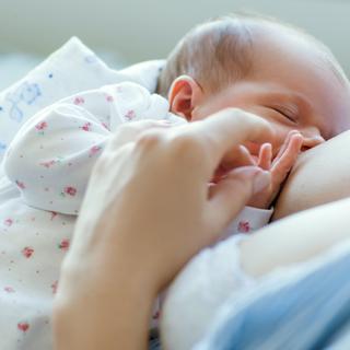 Ein zarter Moment, in dem ein Baby von seiner Mutter gestillt wird.