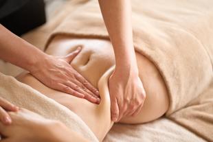 Eine Person, die eine Massage erhält, wobei die Hände sanft Druck auf den Rücken ausüben.