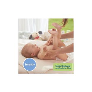 Baby liegt auf dem Rücken auf einer weißen Unterlage, zwei Hände heben sanft die Beine an