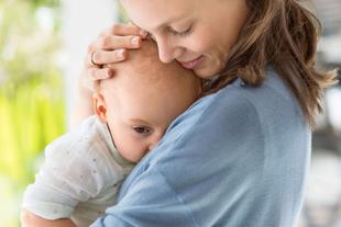 Ein zärtlicher Moment zwischen einer Mutter und ihrem Baby, wobei die Mutter das Baby sanft an ihr Gesicht drückt.