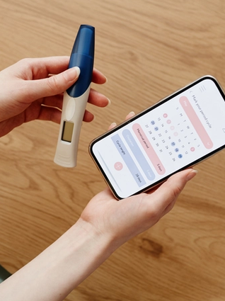 Woman holding ovulation test and cycle tracker