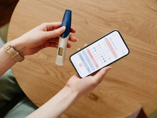 Woman holding ovulation test and cycle tracker
