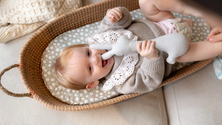 Baby on changing mat playing with a rabbit teddy bear
