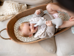 Baby on changing mat playing with a rabbit teddy bear