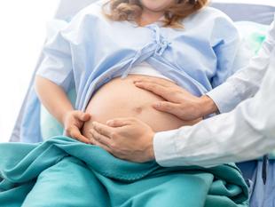 Eine medizinische Fachkraft berührt sanft den Bauch einer schwangeren Frau.
