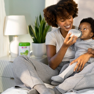 Mum bottle feeding baby in bed