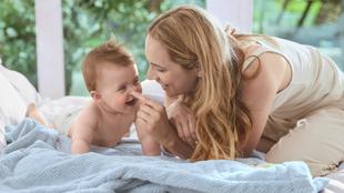 Ein zärtlicher Moment zwischen einer Mutter und ihrem Baby, in dem die Mutter spielerisch das Gesicht des Babys berührt.