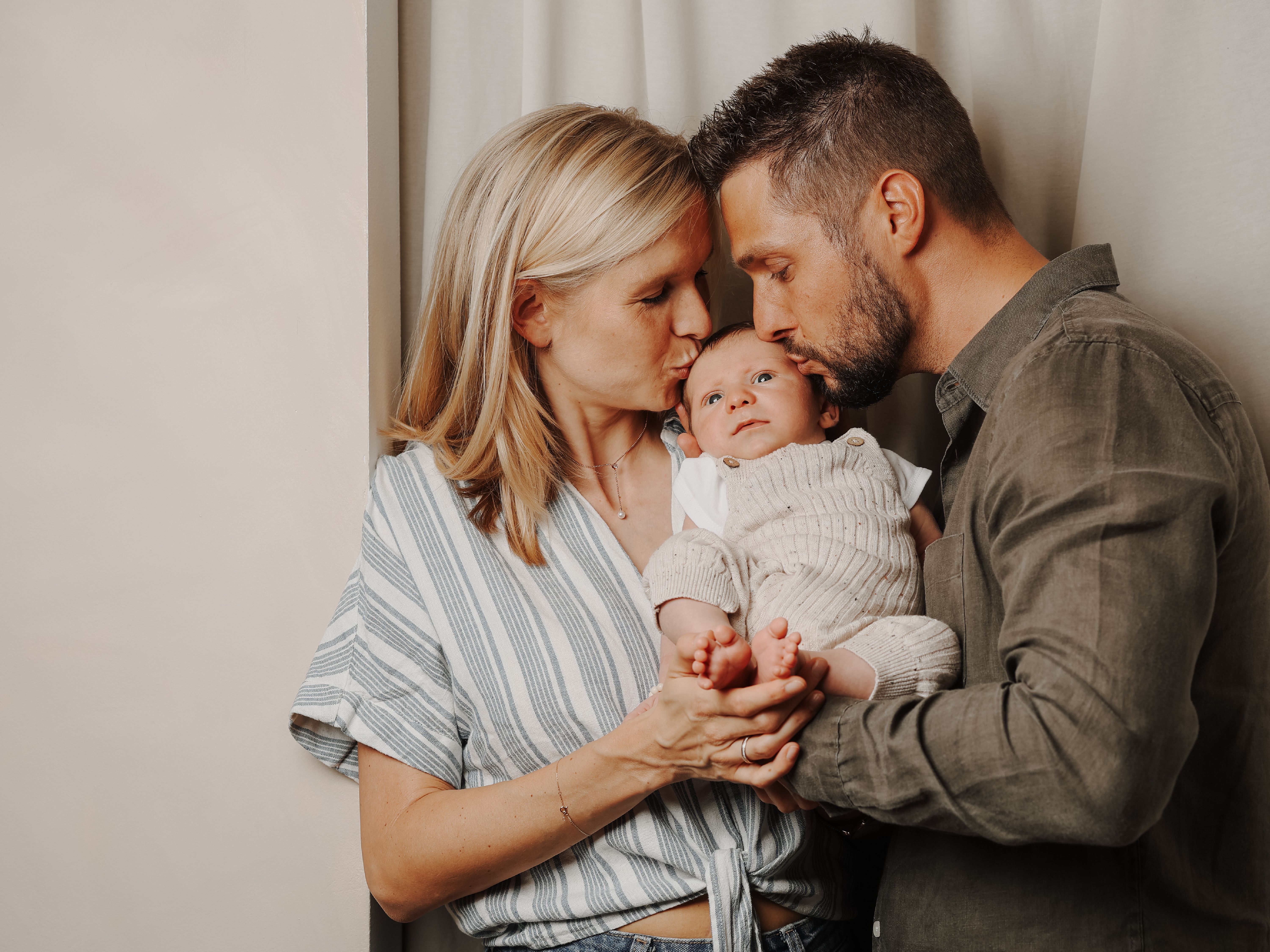 Mutter und Vater mit kleinem Baby in den Armen