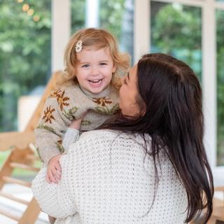 mother holding baby girl who is smiling and looking at the camera.