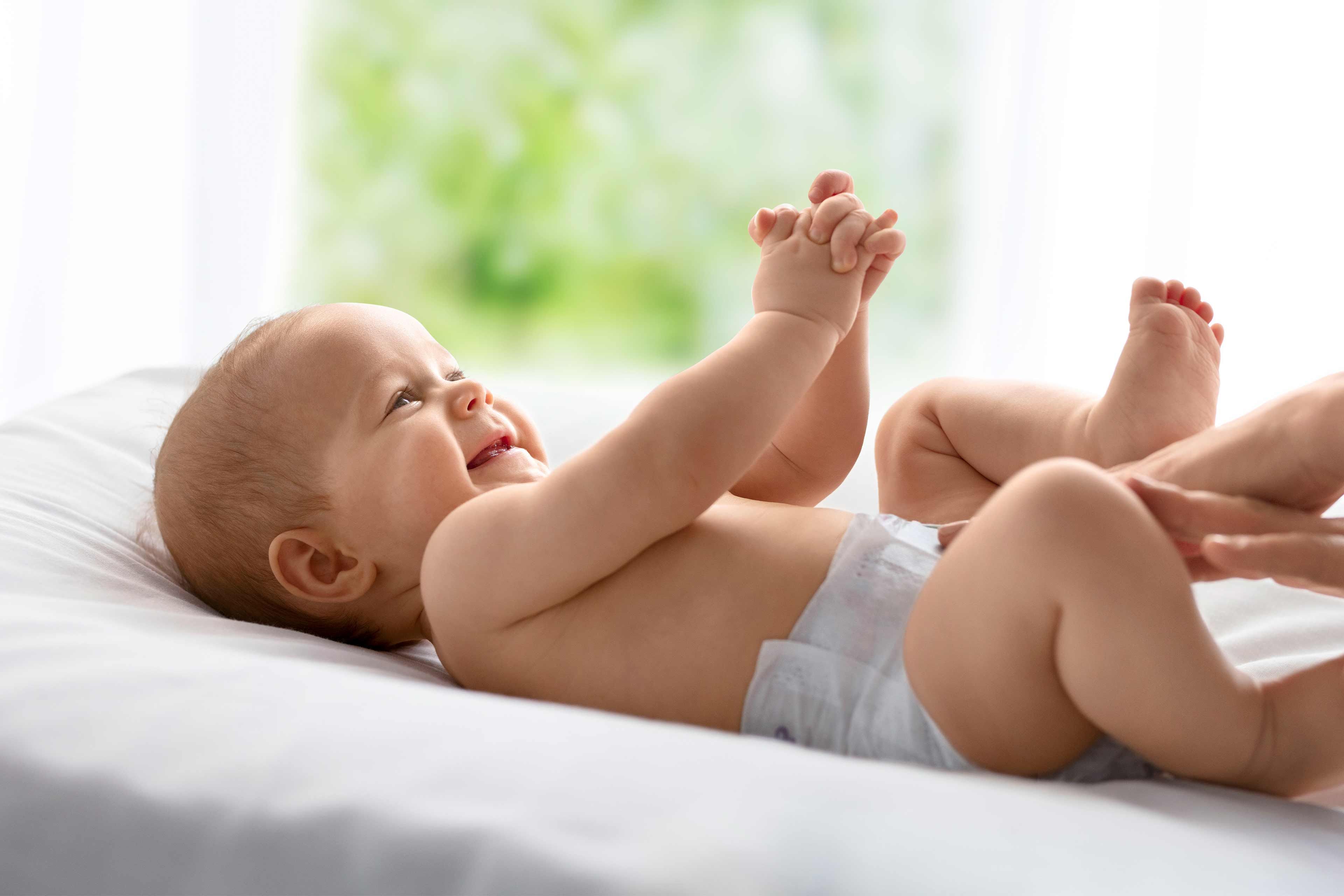 Baby liegt auf dem Wickeltisch und wird gewickelt.