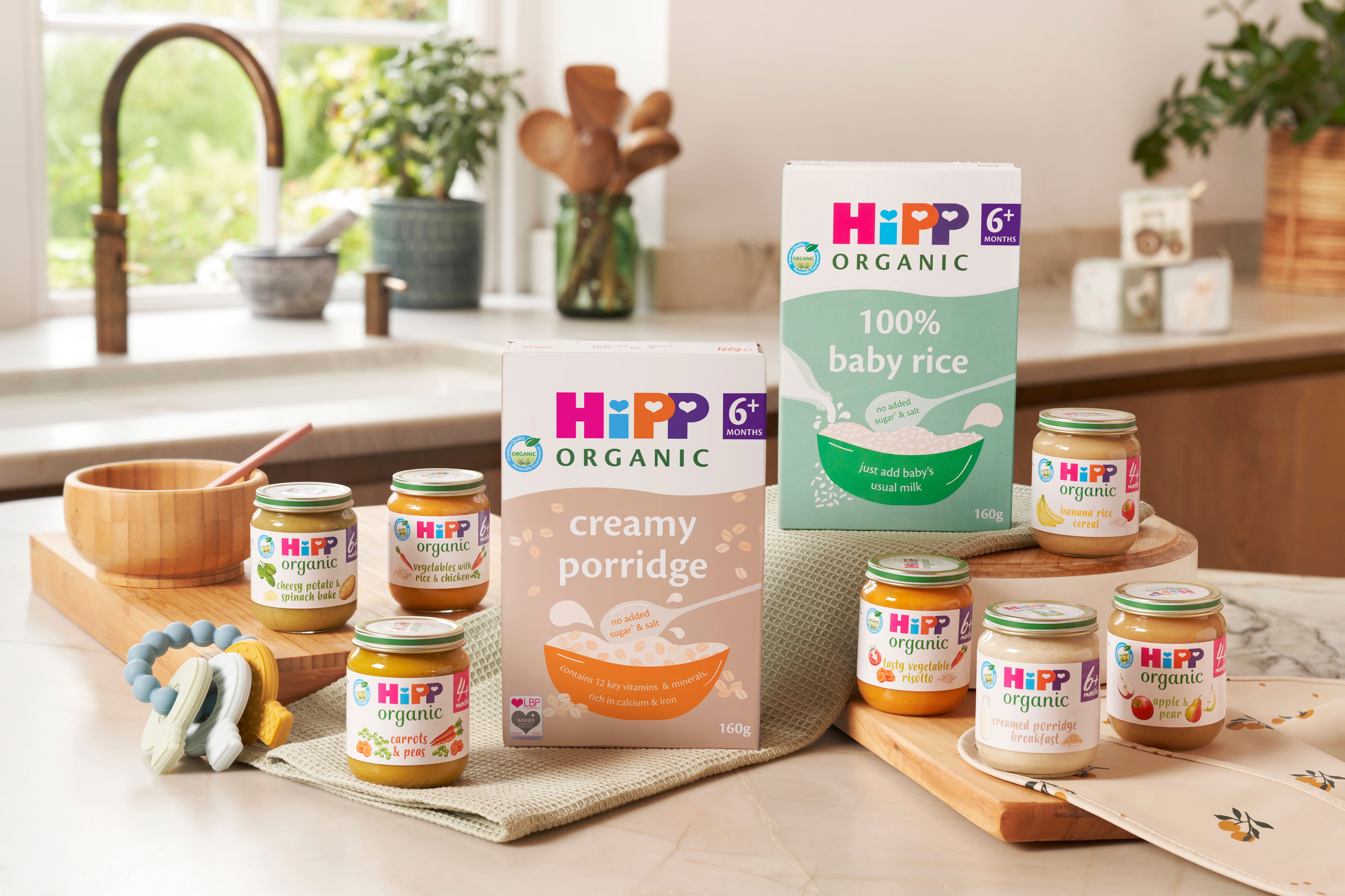 Selection of HiPP Organic baby foods and cereals arranged in a cosy kitchen, ready for starting baby on solid foods.