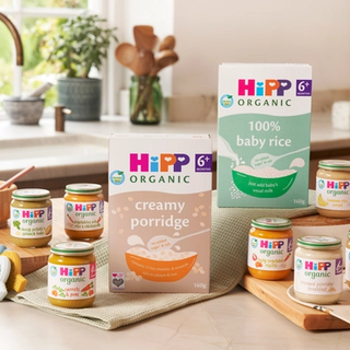 Selection of HiPP Organic baby foods and cereals arranged in a cosy kitchen, ready for starting baby on solid foods.