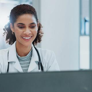Healthcare professional sitting and smiling at her laptop