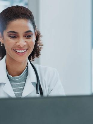 Smiling healthcare professional watching an education video on a laptop in a bright clinic office