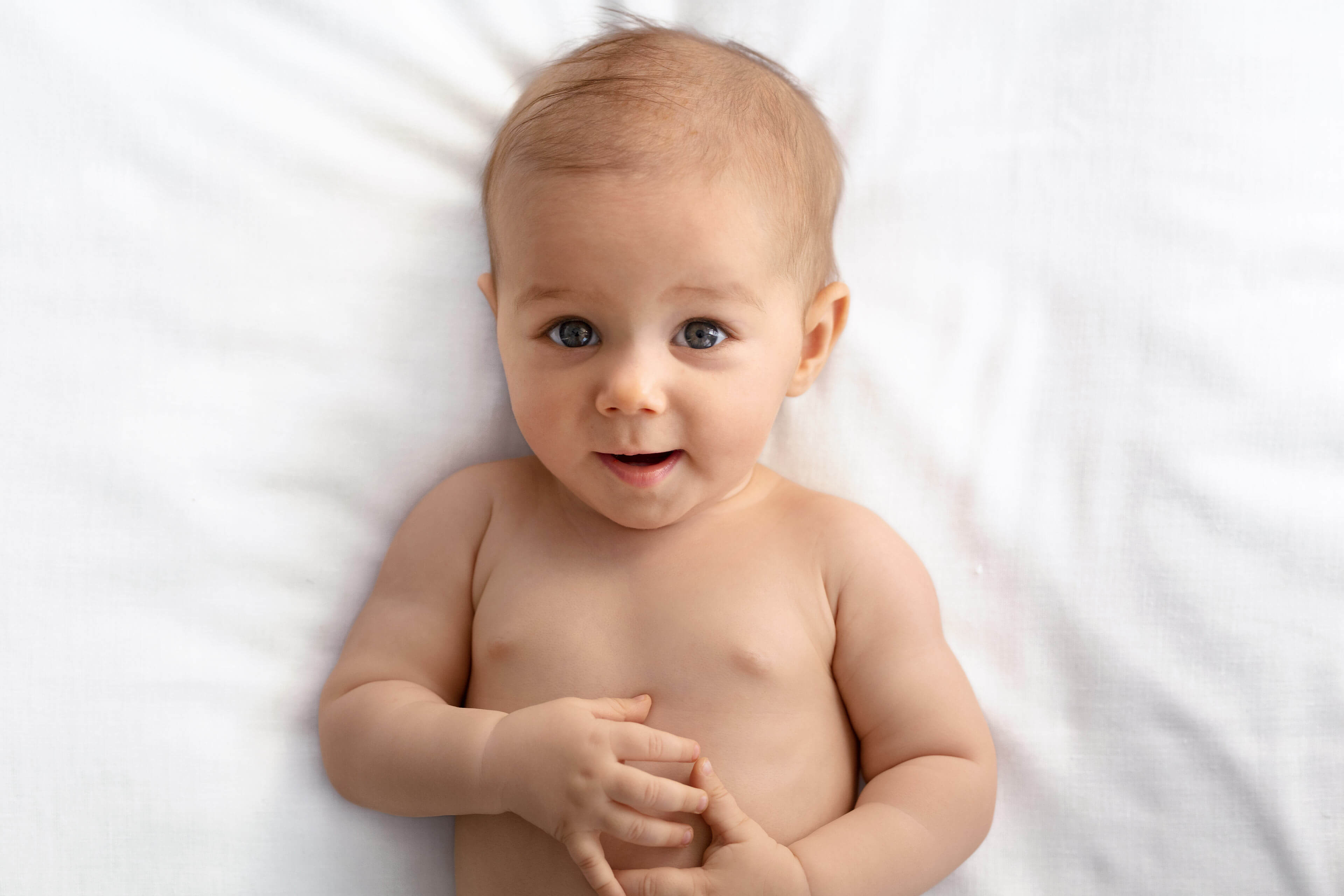 Ein Baby mit blauen Augen, das direkt in die Kamera schaut, vor einem weißen Hintergrund.