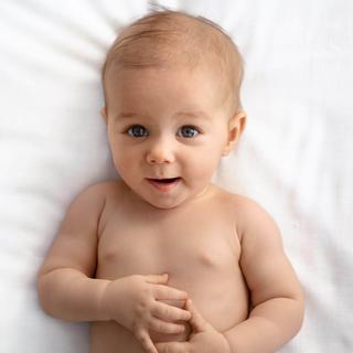 Ein Baby mit blauen Augen, das direkt in die Kamera schaut, vor einem weißen Hintergrund.
