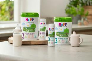 HiPP Organic Stage 2 Follow On Milk and Stage 3 Growing Up Milk tins and ready-to-feed bottles on a kitchen counter.