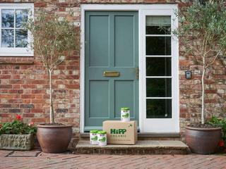HiPP Organic follow on milk powder tins outside the front door of a house next to a delivery box
