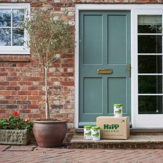 HiPP Organic follow on milk powder tins next to a delivery box outside a front door