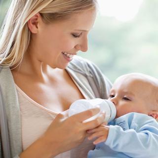 Eine Frau füttert ihr Baby mit der Flasche.