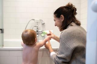 Mum and toddler playing with the HiPP clean and green bubbly bath hippo over a bath