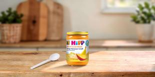 HiPP Bio Frucht & Getreide Mango-Bananen-Grieß 190g Glas auf Holztisch mit Löffel in heller Küche