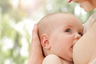 Baby wird liebevoll an der Brust gestillt, nah aufgenommen, ruhige Atmosphäre beim Stillen im Alltag und Beruf