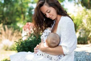 Mutter stillt ihr Baby liebevoll im Grünen und hält es ruhig im Arm