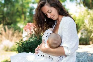 Mutter stillt ihr Baby liebevoll im Grünen und hält es ruhig im Arm
