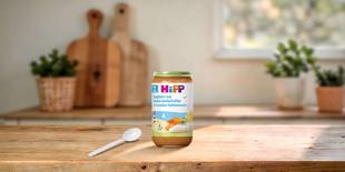 HiPP Bio Babyglas Spaghetti mit Alaska-Seelachsfilet in Gemüse-Sahnesauce ab 12 Monaten auf Holztisch mit Löffel in heller Küche
